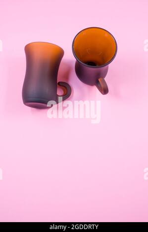 Vertical shot of two brown bell-shaped mugs isolated on pink background Stock Photo