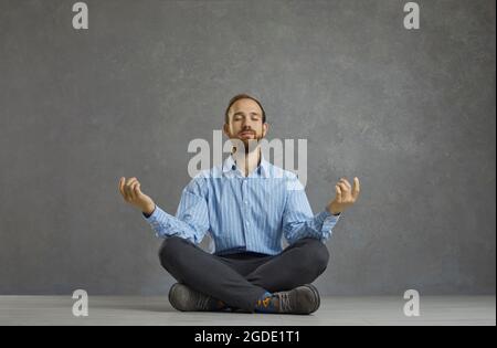Relaxed businessman sitting in lotus pose on floor, meditating and relieving stress Stock Photo