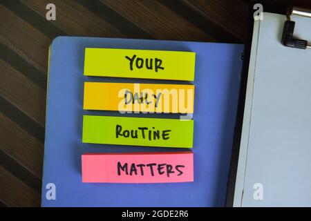 Your Daily Routine Matters write on sticky notes isolated on Wooden Table. Stock Photo