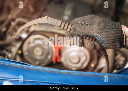 Auto mechanic shows a torn timing belt and peeled teeth on it, close-up Stock Photo