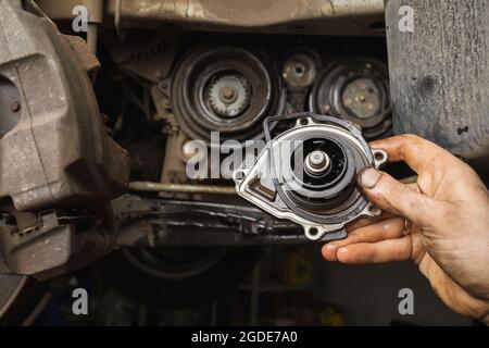 An auto mechanic shows the removed old engine pump Stock Photo