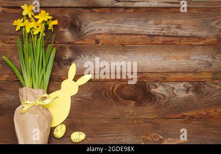Easter bunny, eggs and spring yellow flower on old wooden background. Easter composition with  copyspace for text. Happy Easter Day concept, greeting Stock Photo