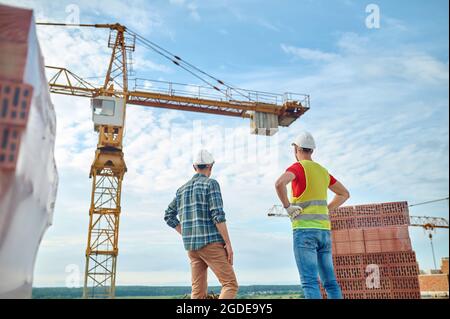 Experienced construction workers in hardhats checking the building site Stock Photo