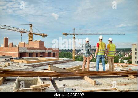 Three men in protective helmets inspecting the building site Stock Photo