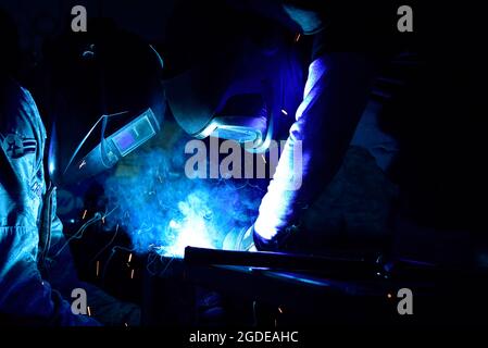 Airman 1st Class Matthew Crozier, 11th Civil Engineer Squadron structural apprentice, left, assists Fabian Moore, welder, as he welds a metal bar in place at Joint Base Andrews, Md., Feb. 13, 2019. (U.S. Air Force photo by Airman 1st Class Noah Sudolcan) Stock Photo