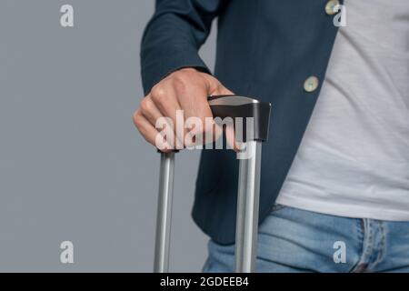 Mans hand holding telescopic handle of suitcase Stock Photo