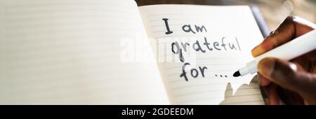 African American Man Writing In Gratitude Journal Stock Photo
