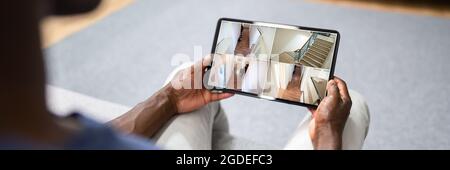 African American Using Security And Alarm System On Tablet Stock Photo