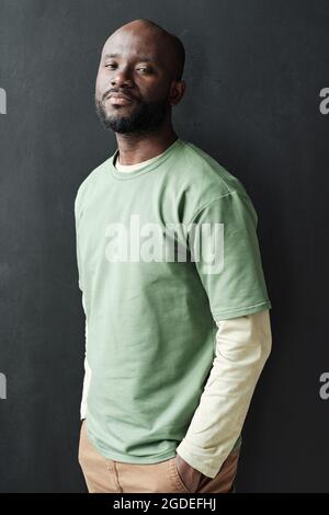 Portrait of African young handsome man in casual clothing looking at camera while standing against the black background Stock Photo