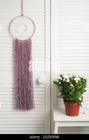 Pink dream catcher with white flowers in the interior Stock Photo