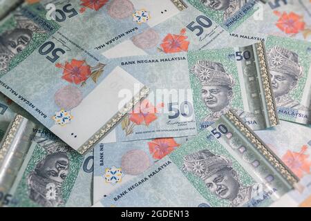 A big pile of Malaysian Ringgit. A large amount of 50 ringgit banknotes. Wildly jumbled bunch banknotes of Malaysia. RM 50 unsorted on a table.  Money Stock Photo