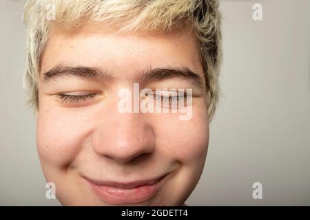 funny close up of teenage boy very close up with small smile and closed eyes Stock Photo