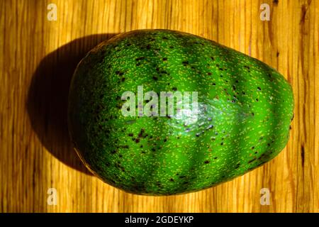 Avocado fruit on a wooden table in the morning light. Stock Photo