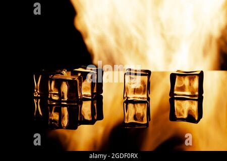 five ice cubes on a black background, in the background flames Stock Photo