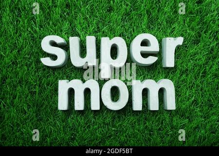 Super Mom made from concrete alphabet top view on green grass Stock Photo