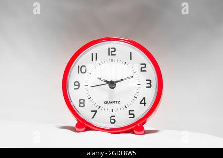 Small red alarm clock show the running time. A modern clock with red frame. Smile face of a clock. Close up on a red plastic watch with second pointer Stock Photo