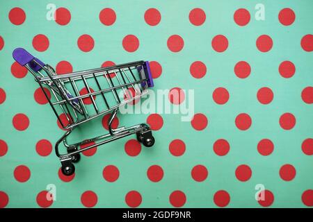 Mini trolley shopping cart on green polka dot background Stock Photo