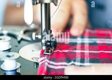 close-up hands of a seamstress at the sewing machine. factory production of clothing. Stock Photo