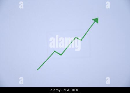 Photo of a green arrow pointing up on white paper, positive trend and result Stock Photo