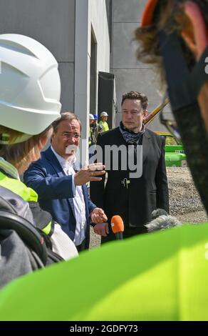 Brandenburg, Germany. 13 August 2021:: Elon Musk (r), Tesla CEO, and Armin Laschet, CDU Federal Chairman and Minister President of North Rhine-Westphalia, speak to journalists in front of what will later be the main entrance to the Tesla Gigafactory. The first vehicles are to roll off the production line in Grünheide near Berlin from the end of 2021. The US company plans to build around 500,000 units of the compact Model 3 and Model Y series here each year. Credit: dpa picture alliance/Alamy Live News Stock Photo