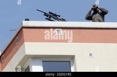 Berlin, Germany. 13th Aug, 2021. Snipers secure the area around the central commemoration ceremony for the 60th anniversary of the construction of the Berlin Wall on Bernauer Strasse from a rooftop. Credit: Wolfgang Kumm/dpa/Alamy Live News Stock Photo