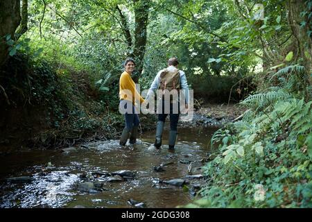 Hiker couple walking in stream Stock Photo