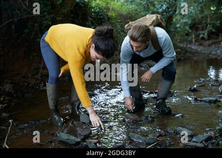 Hiker couple walking in stream Stock Photo