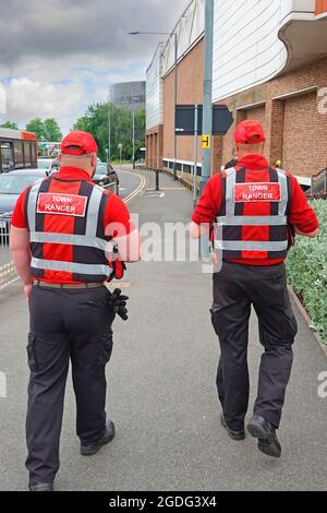 Two Rugby Town Rangers in red uniform patrolling town centre targeting criminal activity direct radio links to CCTV operators & police Warwickshire UK Stock Photo