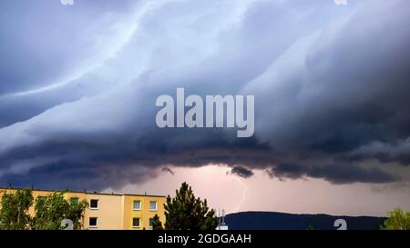 A lightning strike behind a massive shelf cloud over the city Usti nad Labem Stock Photo