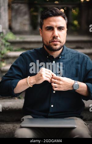 Confident businessman with laptop sitting on steps in city Stock Photo