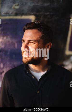 Portrait of happy smiling man standing against wall in city Stock Photo