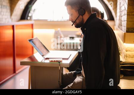 Man in headphones using laptop computer at cafe Stock Photo