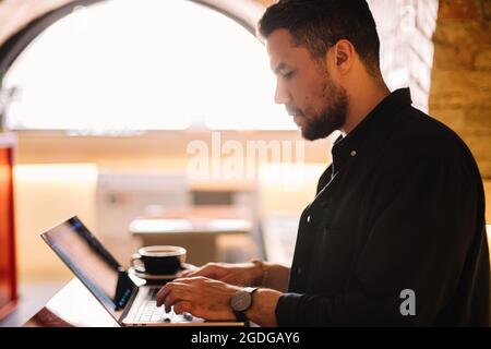 Serious man using laptop computer at cafe Stock Photo