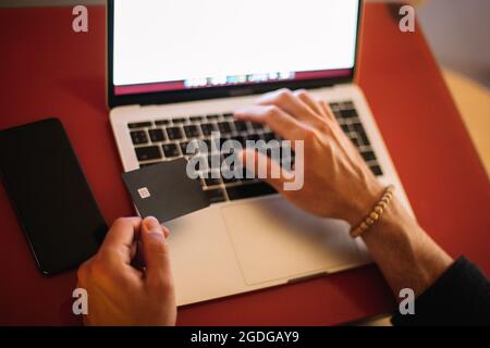 Man using credit card and laptop computer while shopping online at cafe Stock Photo