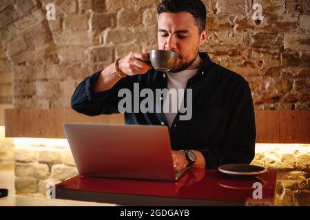businessman drinking coffee while using laptop computer at cafe Stock Photo