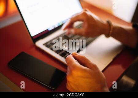 Man using credit card and laptop computer while shopping online at cafe Stock Photo