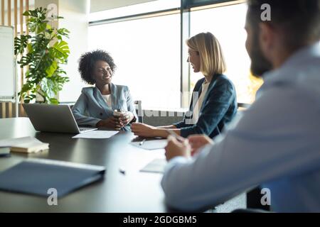 Happy multiracial employees smiling and speaking with each other during seminar Stock Photo
