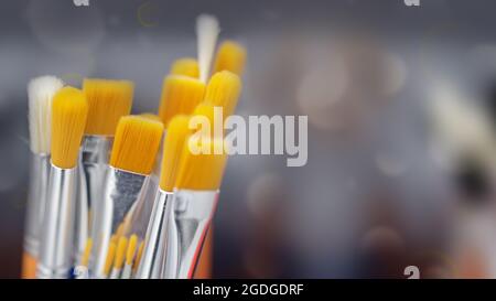 Artist's brushes for painting. Close up of different new painting brushes on gray background with bokeh, soft focus. Stock Photo