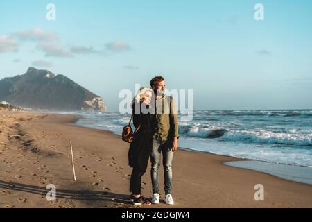 Hipster couple in love looking the sunset on the desert beach during the spring season - Love, travel and adventure concept - Copy space Stock Photo