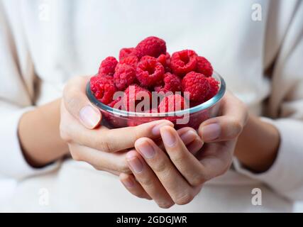 hands holding raspberries in a bowl Stock Photo