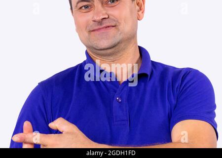 The photo of a smiling man in blue t-shirt having hearing problems and he makes the cross sign with two index fingers.  Stock Photo