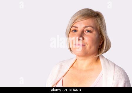 Close up photo of a blonde pretty woman posing for camera, she has pleasant facial expression and a fresh look. Stock Photo