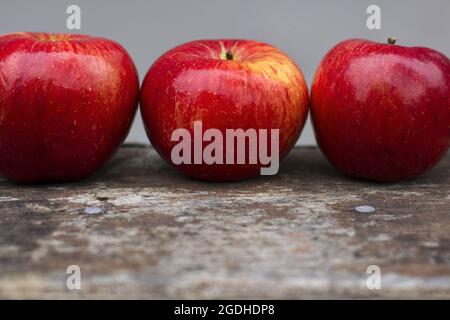 Three red apples on a gray background Stock Photo
