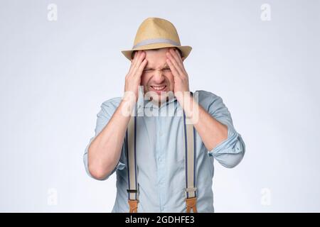 Unhappy caucasian man rubbing temples having terrible headache. Stock Photo