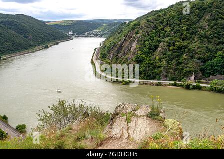 The river Rhine in western Germany flows between the hills covered with forest, visible river bend and rock cliff. Stock Photo