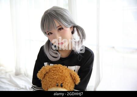 Asian young woman portrait in bed room with bear doll on white tone Stock Photo