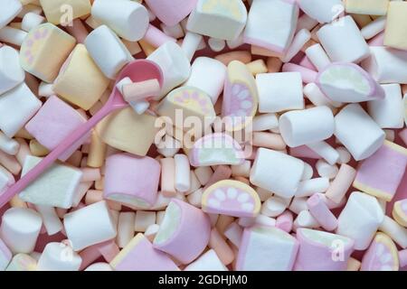 Colorful marshmallows on a pink dish isolated on a pink background. Fluffy marshmallow texture closeup. Stock Photo