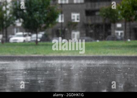 Heavy rain, close-up of splashing and flying drops with an inverted trace and reflection in a puddle. Stock Photo