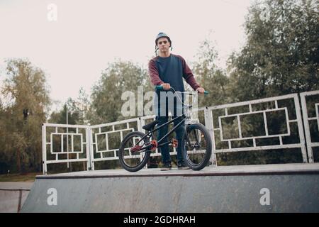 Professional young sportsman cyclist with bmx bike at skatepark Stock Photo