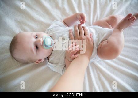 boy lying on bed sucking a pacifier Stock Photo